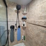 A tiled shower with towels hanging on the wall in a bathroom.