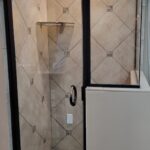 A bathroom with tiled floor and glass door.