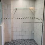 A bathroom with a glass shower door and tiled floor, perfect for a bathroom remodel.