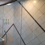 A bathroom with tiled walls and a glass shower door.