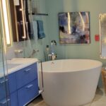 A bathroom with a white tub and blue cabinets for a bathroom remodel.