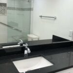 A bathroom with black granite counter tops and a new shower.