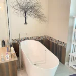 A white bathtub with a tree on it sits peacefully in the bathroom.
