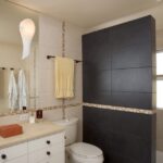 A black tiled bathroom with a toilet and sink, perfect for a quick shower or bathroom refresh.