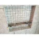 A tiled shower with a shelf, perfect for a bathroom remodel.