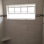 A white tiled shower with a window, perfect for a bathroom remodel.