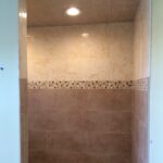 A bathroom with tiled shower and floor.
