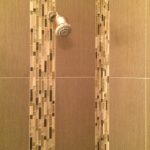 A shower with beige tiling and a shower head.