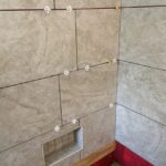 A bathroom with tiled shower and red walls underwent a remodel.