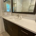 A bathroom with a white sink and mirror for a bathroom remodel.