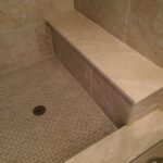 A tiled shower with a bench and tiled floor, perfect for your bathroom remodel.