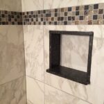 A shower with tiled walls and a shelf, perfect for a bathroom remodel.