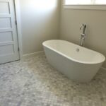 A white bathtub in a bathroom with a white tile floor, perfect for a bathroom remodel.