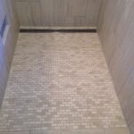 A shower with tiled walls and a tiled floor.