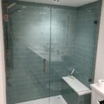 A bathroom with a glass shower door and bench, perfect for a bathroom remodel.