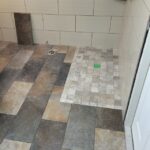 A bathroom with a tile floor and a shower.