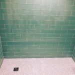 A green tiled bathroom with a white floor.