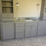A bathroom with gray cabinets and marble countertops.