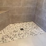 A tiled shower with a tiled floor in the bathroom.