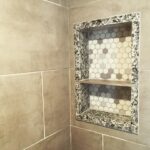 A tiled shower with a shelf.