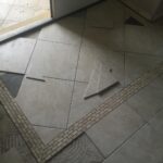 A tile floor with a broken tile in the middle, perfect for a bathroom remodel.