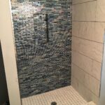 A blue tiled shower with a matching tiled floor, perfect for a bathroom remodel.