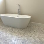 A white bathtub sits in a tiled bathroom.