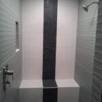A black and white tiled shower with a bench is found in the bathroom.