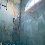 A blue tiled shower in a remodeled bathroom.