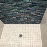 A tiled shower with a blue wall.