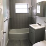 A gray bathroom with a toilet and sink, featuring modern tiling.