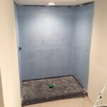 A bathroom is being repainted with blue walls as part of a remodel.
