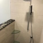 A shower with glass shelves and a modern glass shower head.