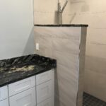 A bathroom remodel with a marble counter top and shower.