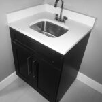 A black and white bathroom sink with a white faucet in a bathroom.
