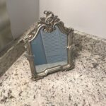 An ornate mirror resting on a counter in a bathroom remodel.