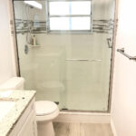A white bathroom with a glass shower door and tiling.