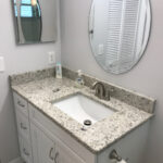 A bathroom with granite counter tops and a mirror.