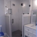 The bathroom features a glass shower stall and toilet.