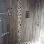A tiled shower in a bathroom with a tiled floor.