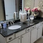 A bathroom with white cabinets and granite countertops.