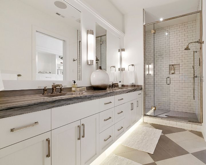 A newly remodeled bathroom with white cabinets and a glass shower.