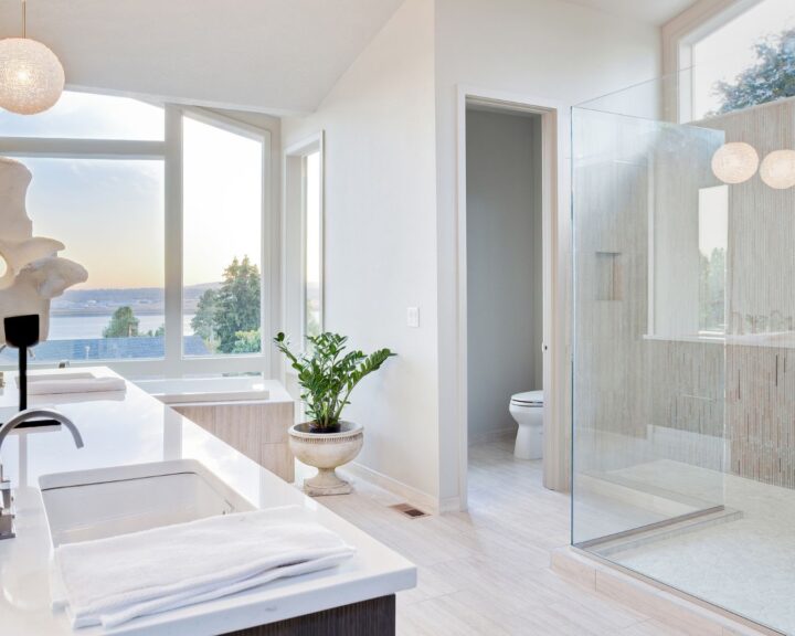 A white bathroom with a glass shower stall and tiling.