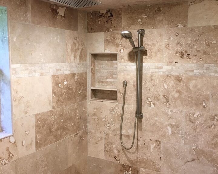 A tiled shower with a beige shower head in a bathroom remodel.