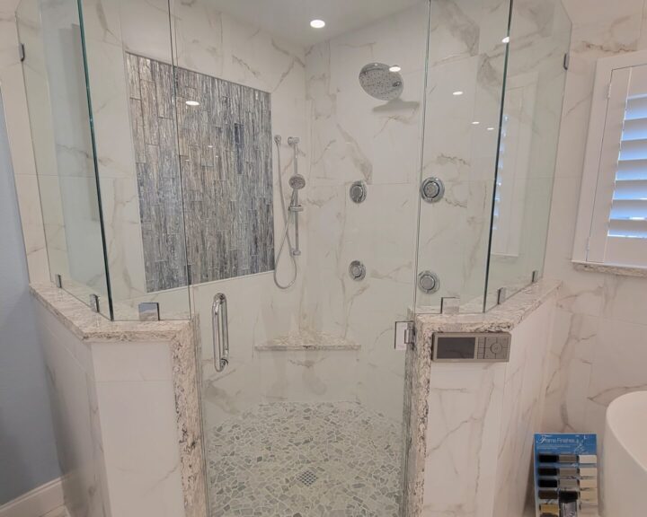 A bathroom with a glass shower door and modern tiling.