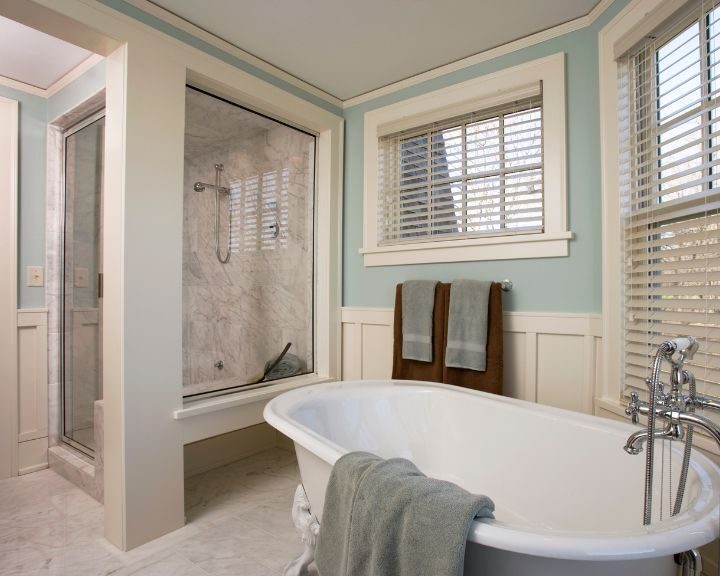 A white bathroom with blue walls and a spacious bathtub.