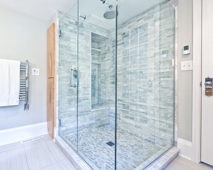 A bathroom with a glass shower door and tiling.