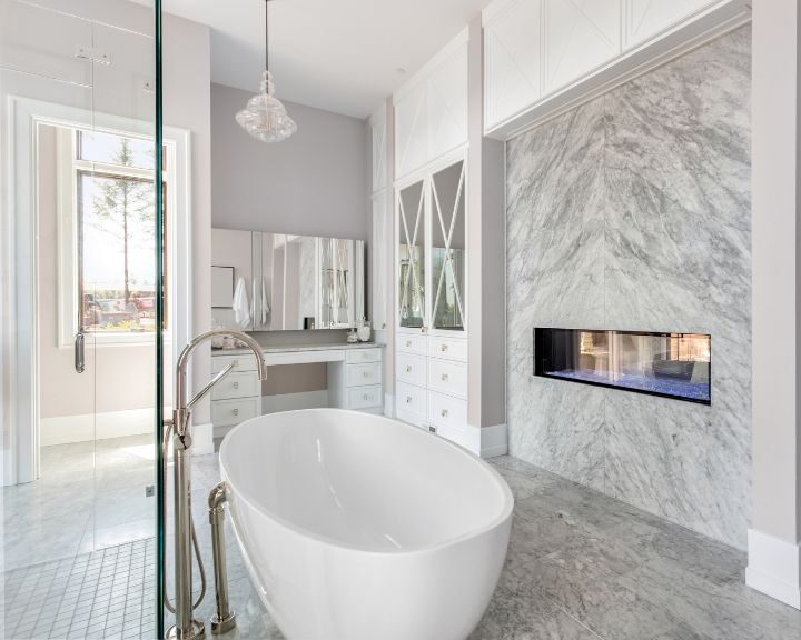 A white bathroom with a marble bathtub and a fireplace.
