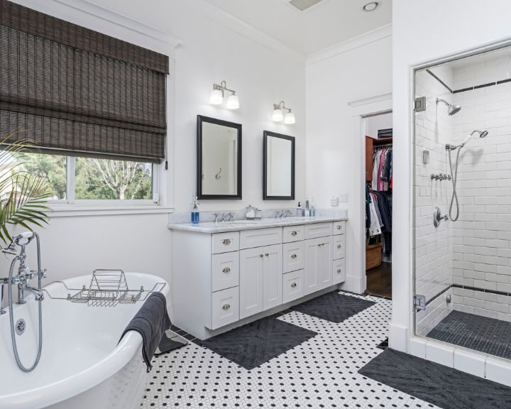 A black and white bathroom with a bathtub for showering.