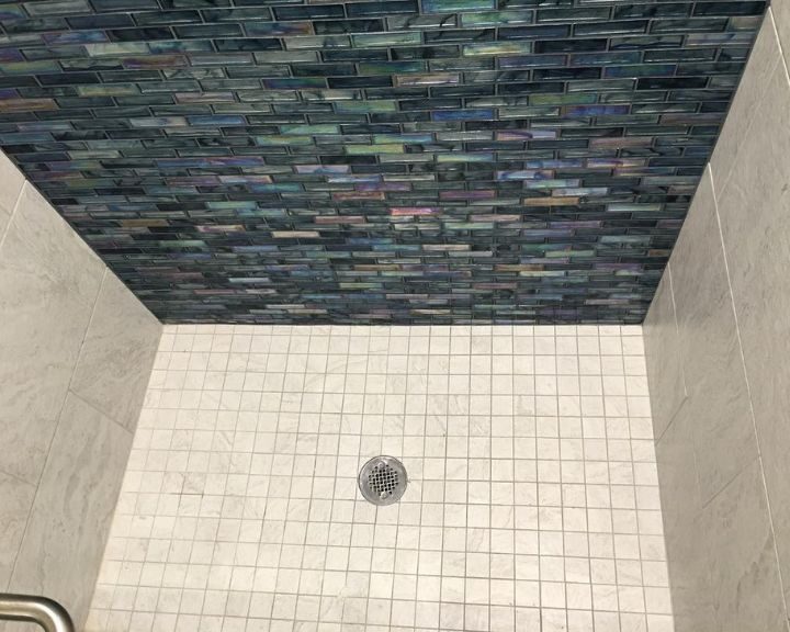 A bathroom with a blue tiled wall in the shower.